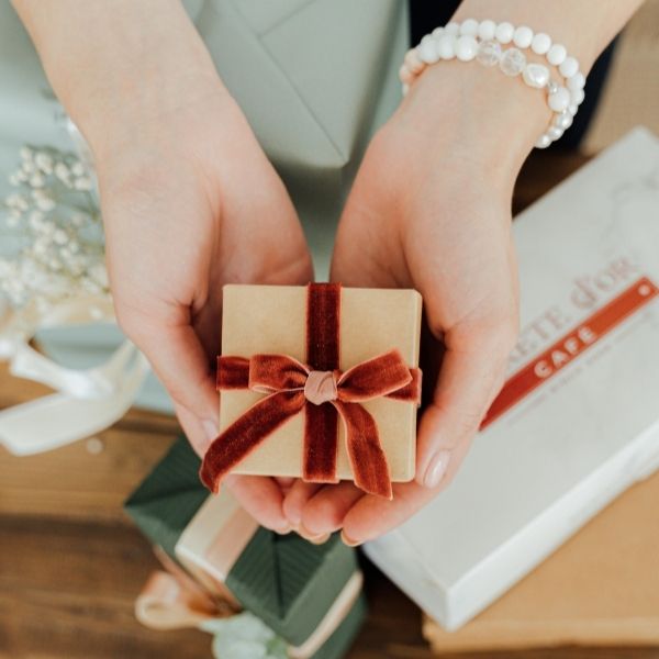 Mujer sosteniendo una caja de regalo de joyas en la mano